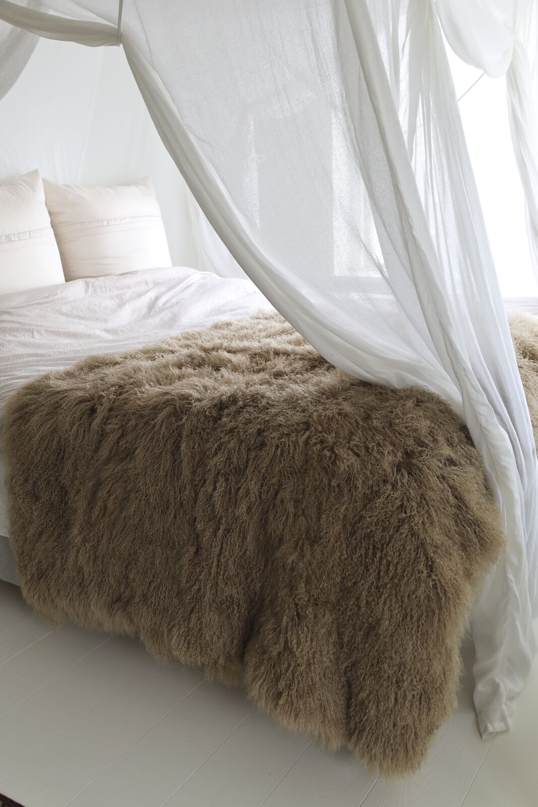Langhaar Lammfell auf einem weissen Bett