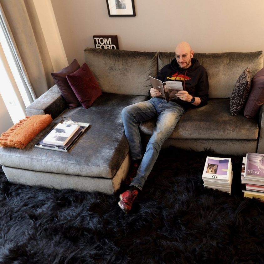 Mann sitzt auf Sofa, das auf ein langhaariges Fellteppich steht