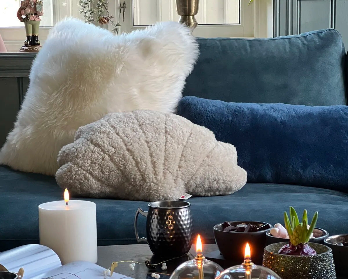 Flauschiges Lammfellkissen und Teddy-Kissen auf blauem Samtsofa