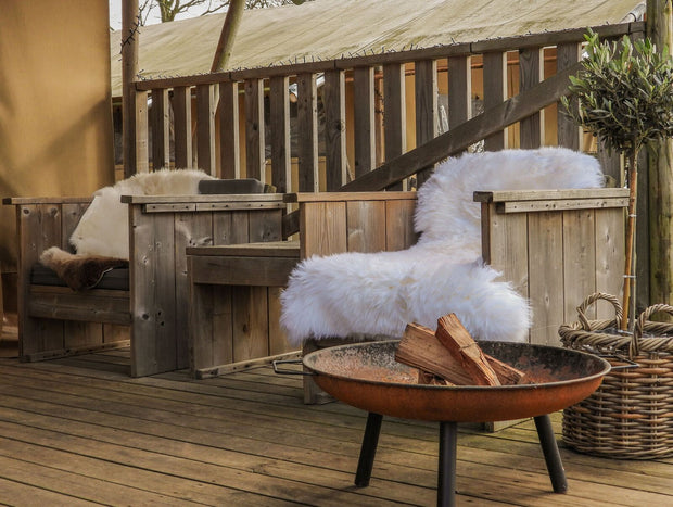 Weisses Schaffell auf einen Holzstuhl neben einer Feuerschale