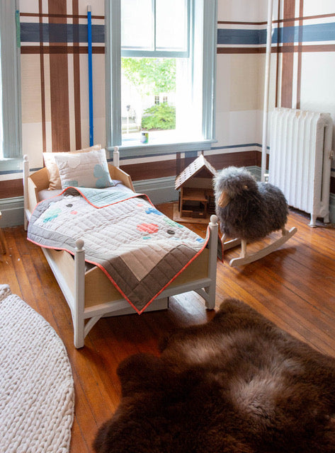 Schaukelschaf steht neben einem Bett in einem Kinderzimmer