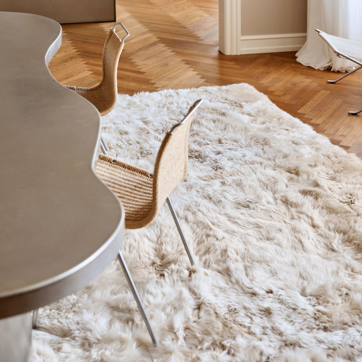 Cremefarbener langhaariger Lammfellteppich unter Esstisch mit Designer-Stühlen auf Parkettboden - großer Lammfellteppich fürs Esszimmer