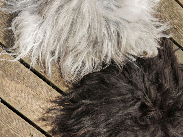 Ein weisses und ein schwarzes Schaffell liegen auf Holzdielen