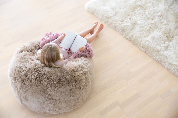 Mädchen sitzt im Fellsitzsack und liest