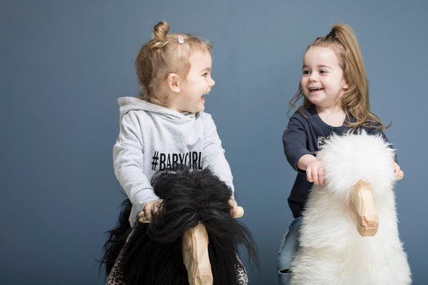 Zwei Kinder, die auf zwei Schaukelschafe sitzen