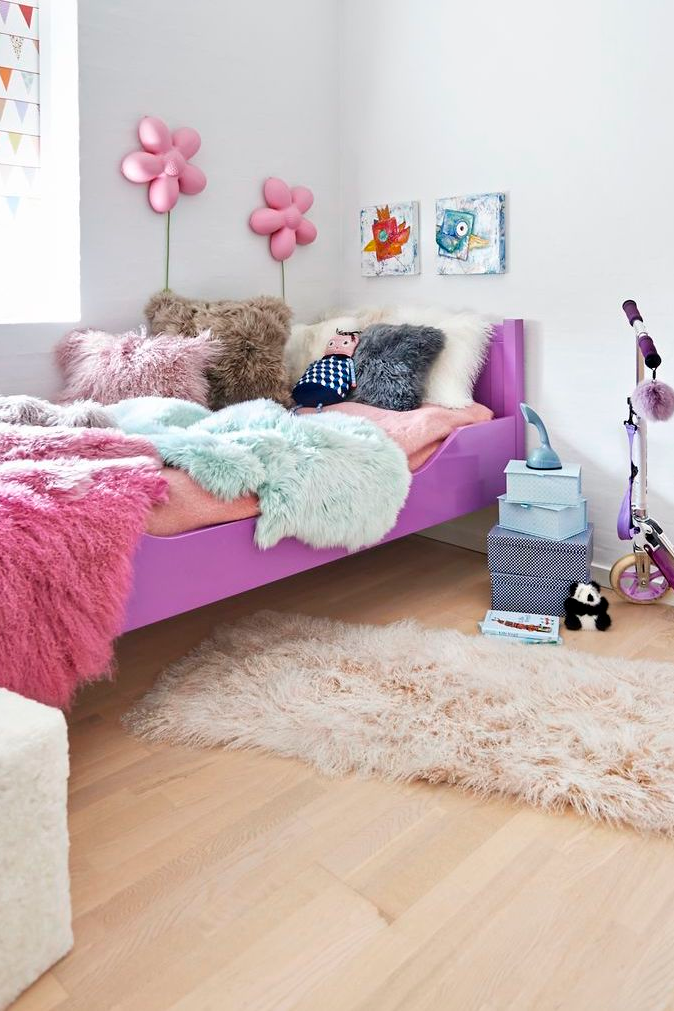 Bett mit Fellkissen in verschiedenen Farben