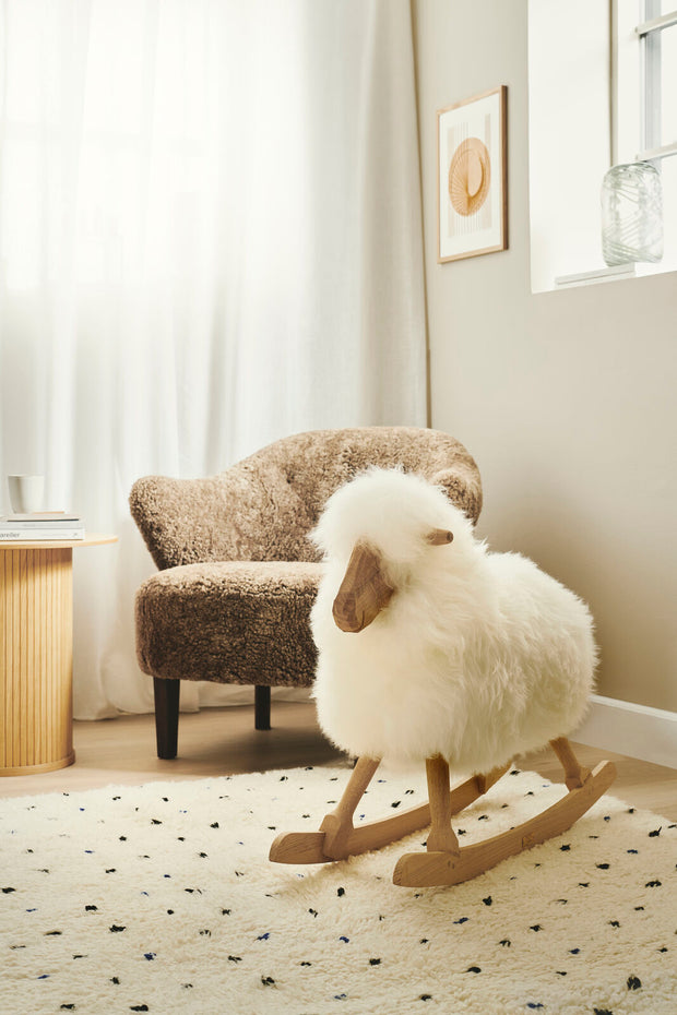 Weisses Schaukelschaf von Povl Kjer vor einem Fellsessel