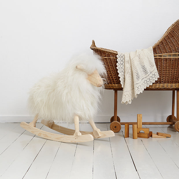 Weisses Schaukelschaf von Povl Kjer steht neben einer Wiege